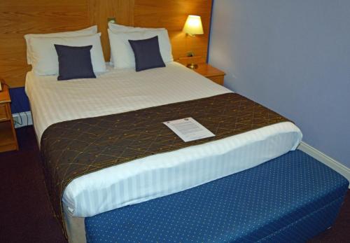 a hotel room with a large bed with a sign on it at Best Western Kings Manor in Edinburgh