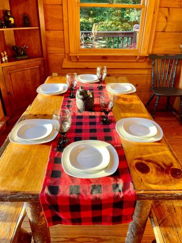 a wooden table with plates and wine glasses on it at Amazing Views~Secluded Retreat~HotTub~GameRoom in Mineral Bluff