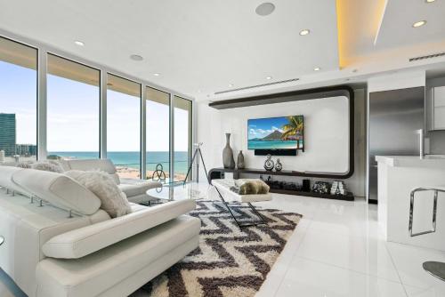 een woonkamer met witte meubels en een grote tv bij Oceanview Penthouse Condo at Decoplage -PH6 in Miami Beach