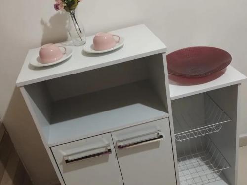 um armário branco com dois pratos cor-de-rosa em cima em Suites Jatiuca em Maceió