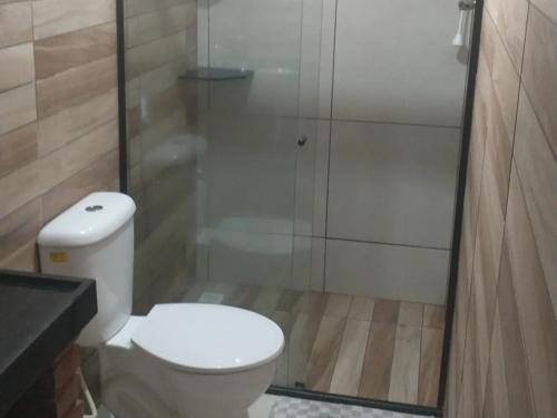 uma casa de banho com um WC e uma cabina de duche em vidro. em Suites Jatiuca em Maceió