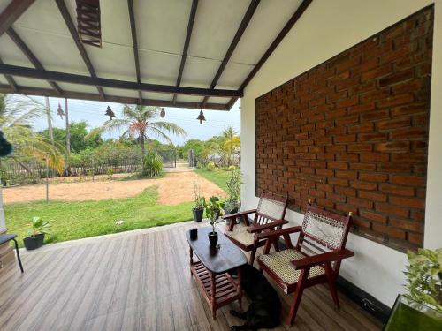 a patio with chairs and a table and a brick wall at Aiden Homestay in Pasikuda