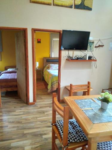 a living room with a table and a tv and a bedroom at Cabaña Tranquila in Villarrica