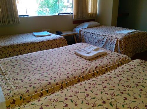 a room with three beds with towels on them at Hostal La Rivera in Huanchaco