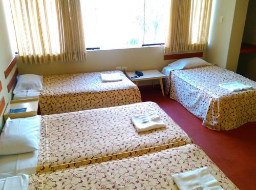 a hotel room with three beds and a window at Hostal La Rivera in Huanchaco
