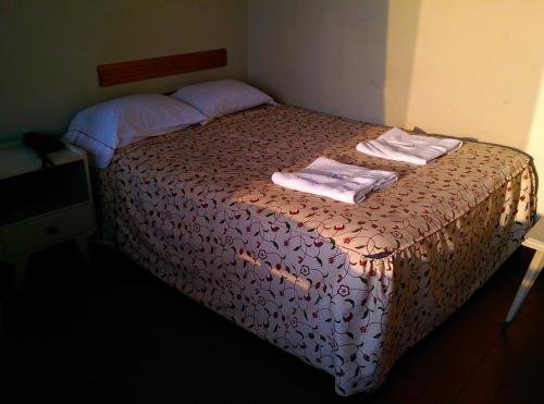 a bedroom with a bed with two towels on it at Hostal La Rivera in Huanchaco