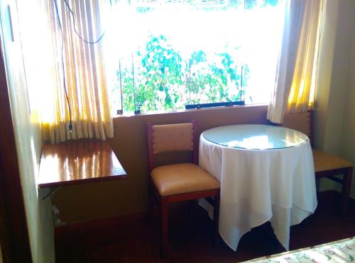 a room with a table and a chair and a window at Hostal La Rivera in Huanchaco