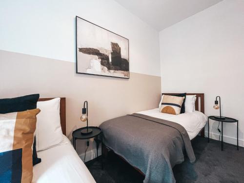 1 dormitorio con 2 camas y 2 lámparas en Coronation House by Solace Stays, en Merthyr Tydfil