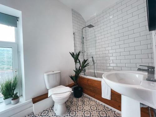 a bathroom with a toilet and a sink and a tub at Coronation House by Solace Stays in Merthyr Tydfil