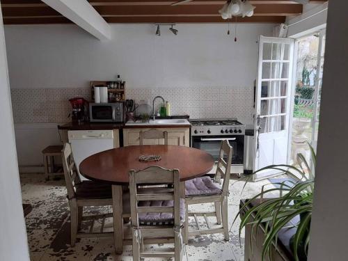 uma cozinha com uma mesa de madeira e cadeiras em La Volière em Champigny-sur-Veude