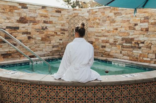a woman sitting in front of a swimming pool at Hotel Carmel in Carmel