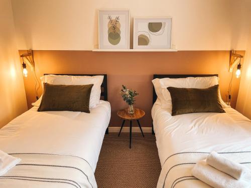 2 Betten in einem kleinen Zimmer mit einem Tisch in der Unterkunft Hollybush Apartment, by Solace Stays in Newport
