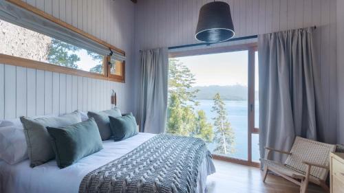a bedroom with a bed and a large window at Savia Madre Eco-lodge in Villa La Angostura