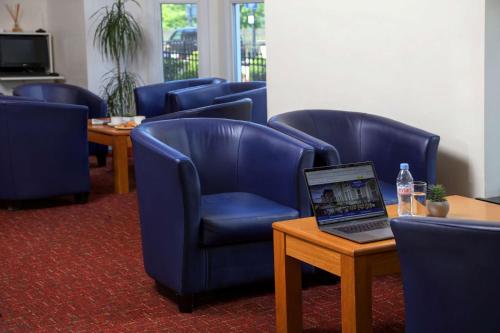 a waiting room with blue chairs and a laptop on a table at Best Western London Highbury in London