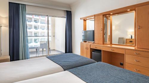 a hotel room with a bed and a television at Ukino Palmeiras Village - 24h All Inclusive in Armação de Pêra