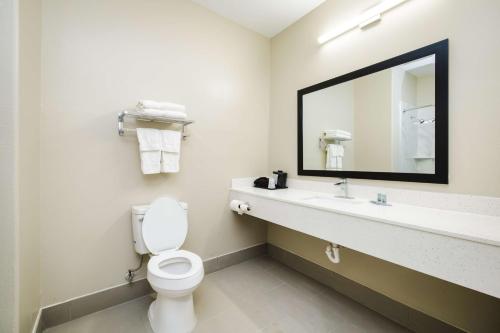 a bathroom with a toilet and a sink and a mirror at SureStay Studio by Best Western Conroe Downtown in Conroe