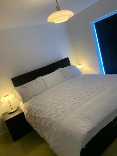a bedroom with a large white bed with two lamps at Brand New Posh 1 Bed Lakeside Flat No parties No Events in West Thurrock
