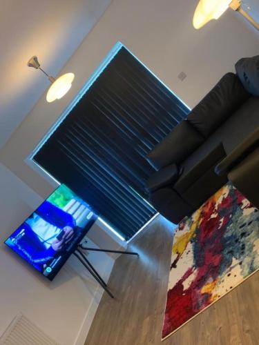a living room with a black couch and a television at Brand New Posh 1 Bed Lakeside Flat No parties No Events in West Thurrock