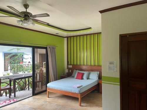 a bedroom with green walls with a bed and a balcony at Hotel Oasis Port Barton in San Vicente