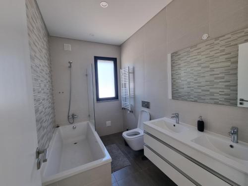 een badkamer met 2 wastafels, een bad en een toilet bij Villa Joia in Bombarral