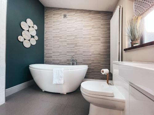 a bathroom with a white tub and a toilet at Ty Fry Gardens in Cardiff