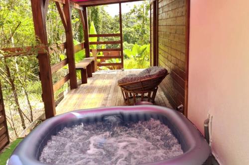 a jacuzzi tub on a porch with a chair at Maison de campagne avec piscine et spa in Lamentin