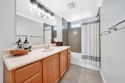 ein Bad mit einem Waschbecken, einem Spiegel und einer Dusche in der Unterkunft Private Heated Pool Oasis/Disney/Retro Arcade/Gym in Placentia