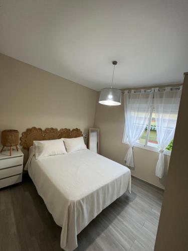 una camera da letto con un grande letto bianco e una finestra di Apartamentos PENSI a Jódar