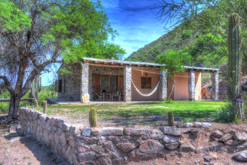 a house with a stone wall in front of it at Finca Puesta del sol in San Agustín de Valle Fértil