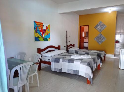 1 dormitorio con 2 camas, mesa y sillas en Pousada Canaã, en Tamandaré