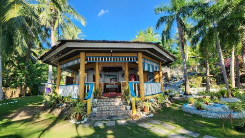 a house with a porch with palm trees at Islanders Paradise Beach in Larena