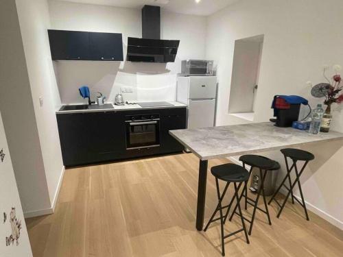 eine Küche mit einer Theke und einem Tisch mit Stühlen in der Unterkunft Appartement T2 à centre ville in Brive-la-Gaillarde