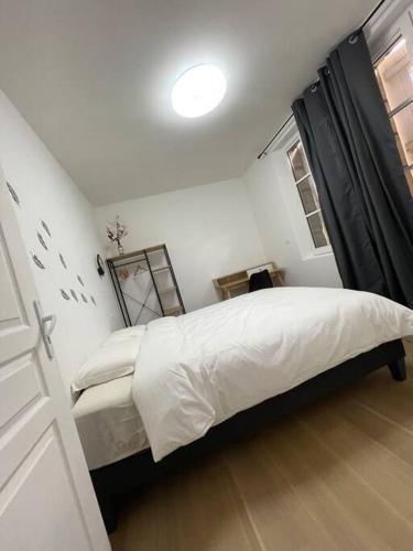 une chambre avec un lit avec des draps blancs et une fenêtre dans l'établissement Appartement T2 à centre ville, à Brive-la-Gaillarde