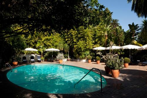 una piscina en un patio con sombrillas en Chateau Marmont en Los Ángeles