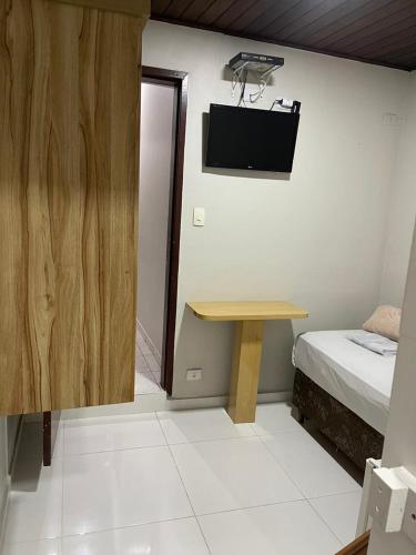 a room with a bed and a table and a tv at Hotel Carrão in Sao Paulo