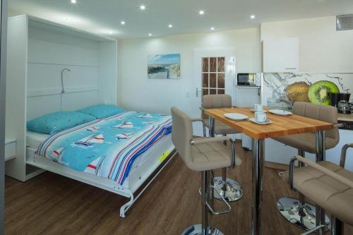 ein Schlafzimmer mit einem Bett und einem Tisch sowie eine Küche in der Unterkunft Prinz Hamlet App. 16  in Neustadt in Holstein