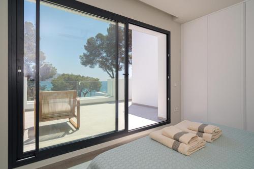 Schlafzimmer mit einem großen Fenster und einem Bett mit Kissen in der Unterkunft BALILOS 4 - By Almarina Villas in Benissa