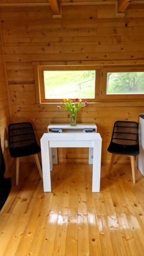 a white table with flowers in a room with two chairs at NEO resort jezero Bruje in Erdevik