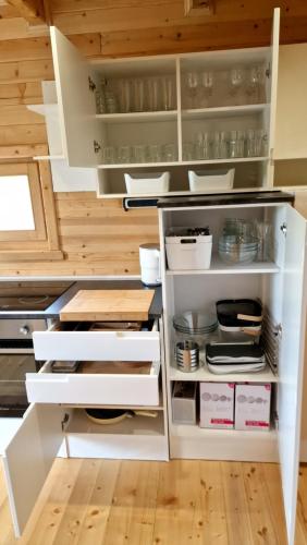an open kitchen with white cabinets and wooden floors at NEO resort jezero Bruje in Erdevik