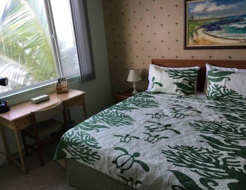 a bedroom with a bed and a desk and a window at Beautiful Oceanfront Welcomes you at Hale Kona Kai 203 by Casago Kona in Kailua-Kona