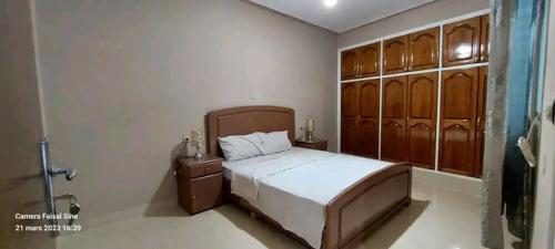 a bedroom with a bed with wooden cabinets and a shower at Appartement ahfir in Ahfir