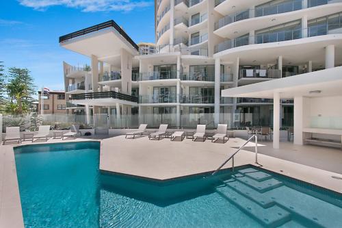 a swimming pool in front of a large building at The Garland at Rainbow Bay in Gold Coast