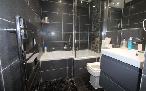 a bathroom with a tub and a toilet and a sink at Modern newly decorated 25 Min from City of London in London