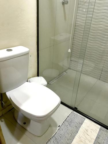a bathroom with a toilet and a glass shower at Chalé nas Árvores in São Francisco Xavier