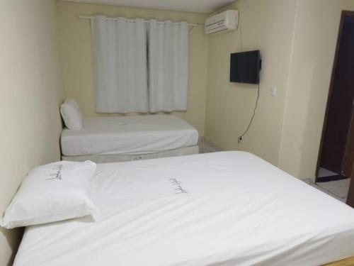 two white beds in a room with a tv at Seabra serviços de hotelaria limitada in Brasilia