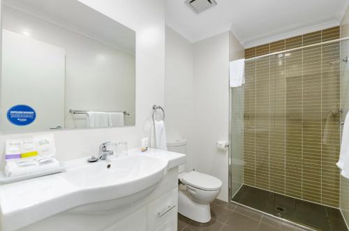 a bathroom with a sink and a toilet and a shower at Quality Suites Pioneer Sands in Wollongong