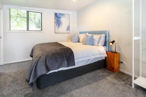 Un dormitorio con una cama con paredes blancas y una ventana en St Albans Gem Single level studio with Queen bed en Christchurch