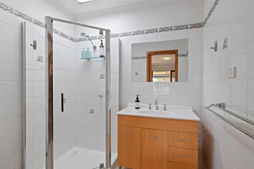 ein weißes Bad mit einer Dusche und einem Waschbecken in der Unterkunft Redwood Beach House - with 10 percent off until September in Cowes