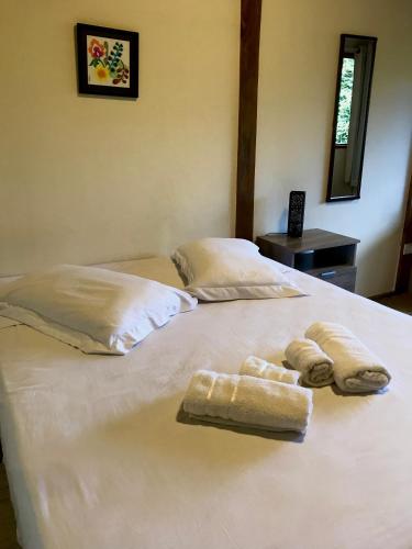 two towels on a white bed in a room at Chalé nas Árvores in São Francisco Xavier