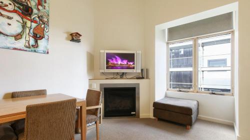 a living room with a table and a television on a fireplace at Chalet Hotham 17 in Mount Hotham